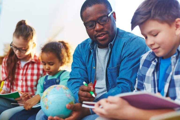 A teacher working through a lesson with young students around a globe in a classroom