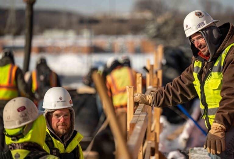 McGough construction crew in hard hats and cold-weather high-visibility gear at a winter formwork pour
